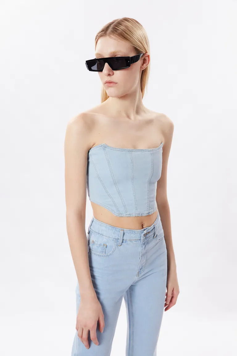 Top corsetero de denim celeste con costuras que moldean la figura de Naíma en Tops para argentina