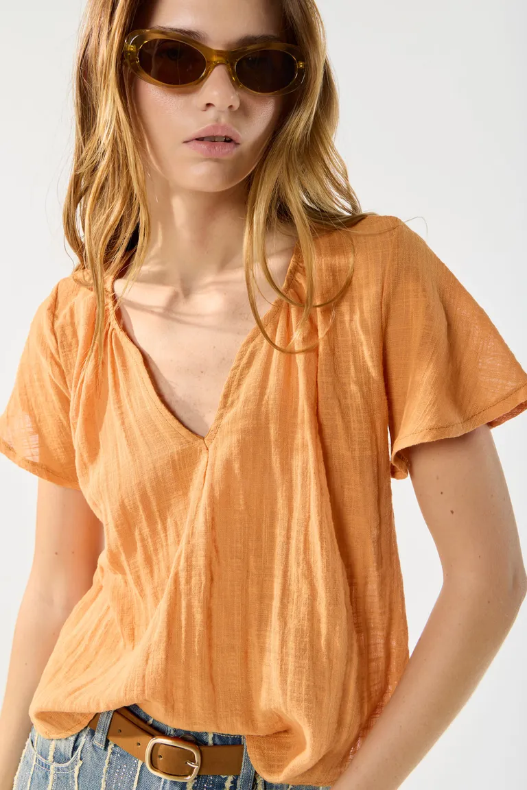 Blusa naranja con escote redondo y detalles de fruncidos, prenda versátil y elegante de Cuesta Blanca en Blusas para argentina