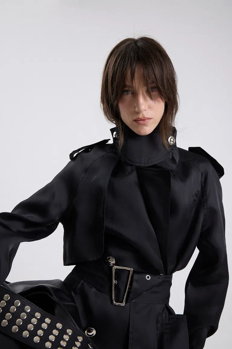 Trench largo con cierre de cinturón, hebillas metálicas y botones frontales en estructura de diseño recto de Maria Cher en Tapados para argentina