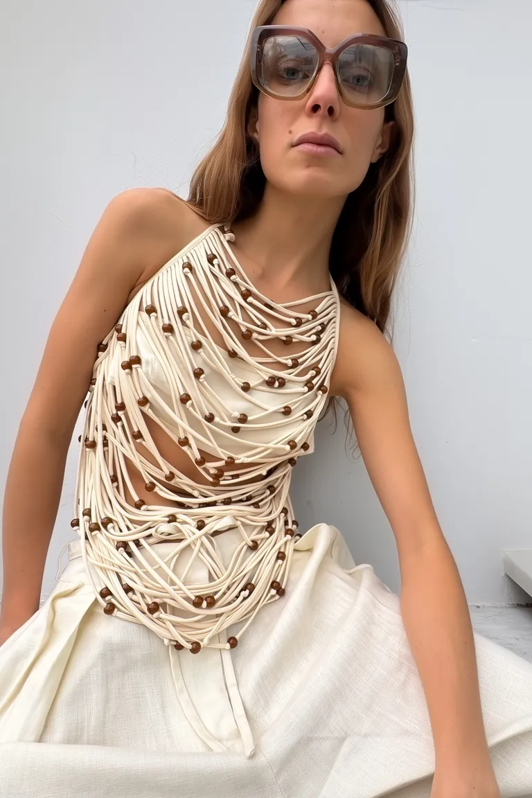 Top de tiras entrelazadas con cuentas en contraste, diseño halter y efecto de movimiento de Maria Cher en Tops para argentina