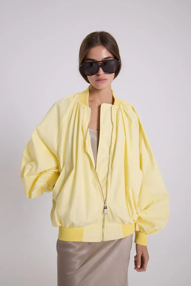 Campera bomber amarilla de gabardina liviana con silueta envolvente y detalles funcionales de Maria Cher en Chaquetas para argentina