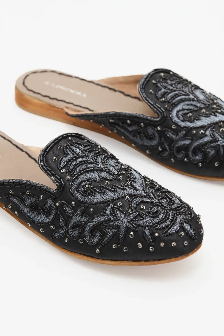 Zuecos negros con bordado decorativo en tonos plateados para un look sofisticado y femenino de Rapsodia en Zuecos Planos para argentina