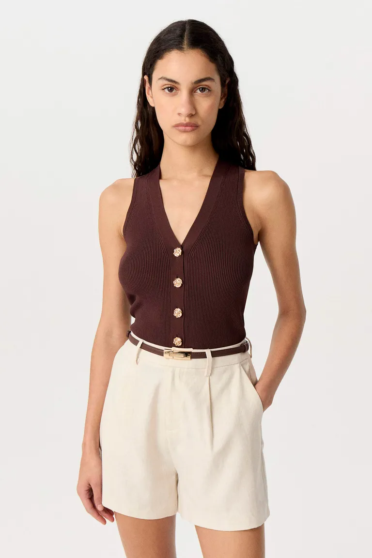 Chaleco tejido con escote en V y detalles metálicos, perfecto para combinar con sastrería de Markova en Chalecos para argentina