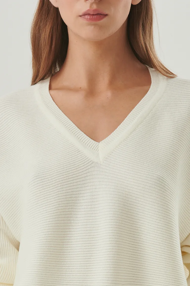 Suéter de punto blanco con escote en V y corte relajado, prenda versátil para looks casuales y urbanos de Sweet en Buzos y Sweaters para argentina
