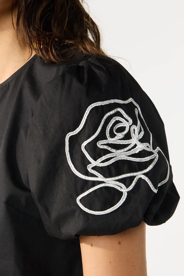 Blusa con mangas abullonadas, bordados decorativos y detalle de volado en el ruedo inferior de Cuesta Blanca en Blusas para argentina