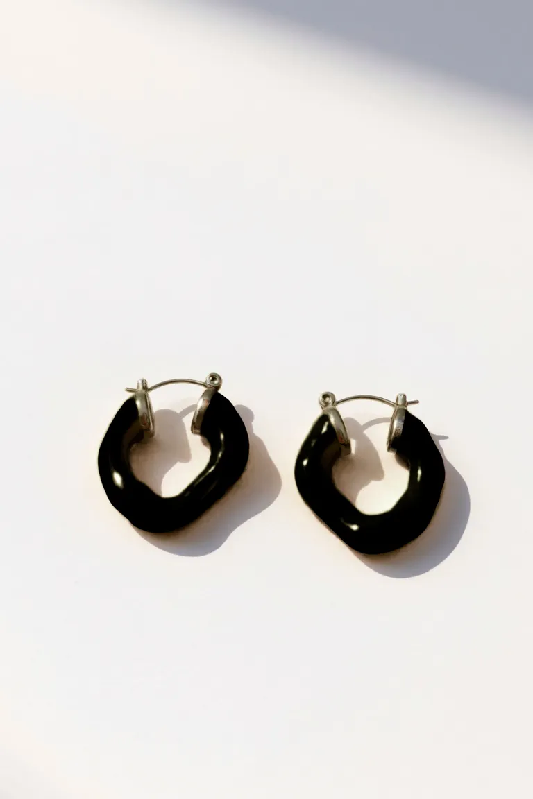 Aros negros de acabado brilloso con forma orgánica y textura lisa de Maria Cher en Bijouterie para argentina