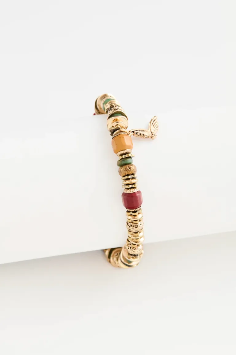 Pulsera con cuentas cilíndricas pequeñas y dije colgante con detalle metálico en la muñeca de Rapsodia en Bijouterie para argentina