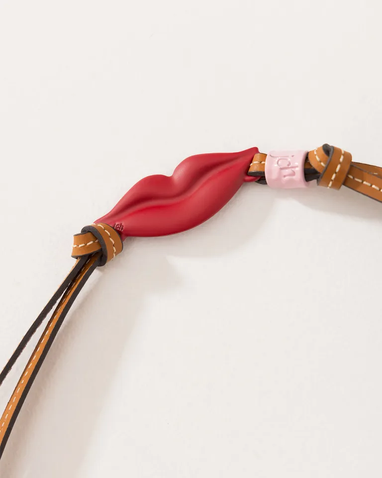 Accesorio colgante de cuero con dije metálico en forma de labios, diseño exclusivo de Jazmin Chebar en Bijouterie para argentina