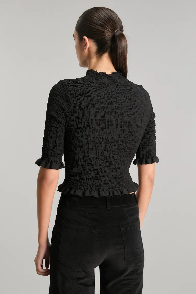 Top negro de diseño minimalista con detalles de volados en cuello, mangas y ruedo de Kosiuko en Tops para argentina