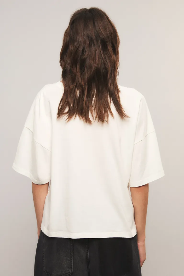 Remera de corte boxy con cuello redondo, mangas cortas y estampa frontal de cadenas con dijes de Kosiuko en Remeras para argentina