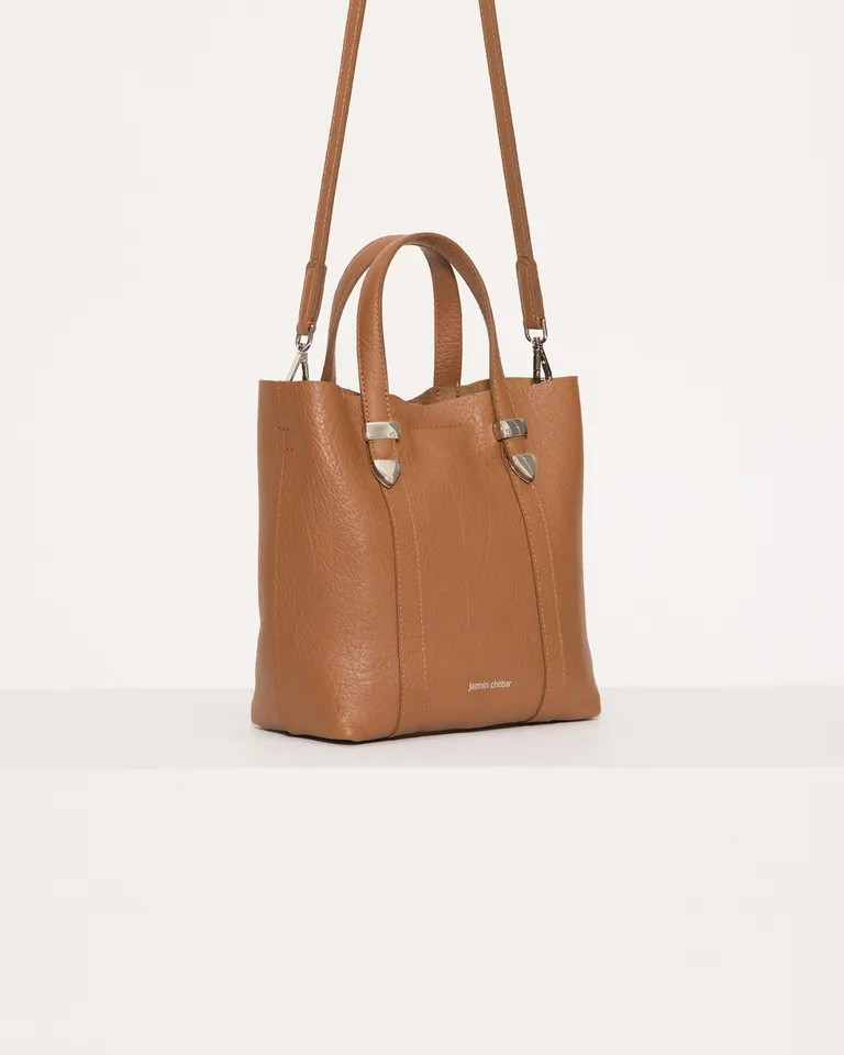 Tote de cuero marrón con detalles metálicos, ideal para el uso diario de Jazmin Chebar en Bolsos y Carteras para argentina